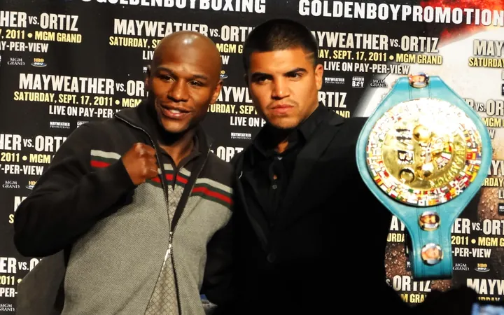 Floyd Mayweather Jr. and Victor Ortiz posing beside the WBC championship belt