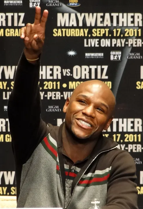 Floyd Mayweather Jr. smiling and making a peace sign at a press conference